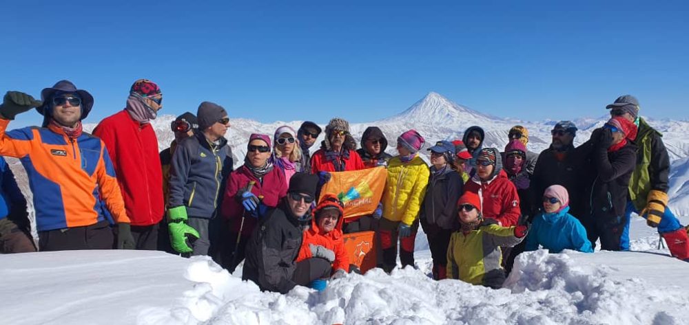 تیم باشگاه کوهنوردی سرکچال بر فراز قله ریزان با نمای زیبایی از دماوند باشکوه در پشت صحنه